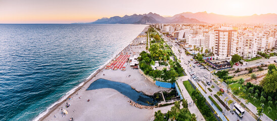 Aerial view of scenic and popular Konyaalti beach in Antalya resort town. Majestic mountains with haze in the background. Vacation and holiday in Turkiye - obrazy, fototapety, plakaty