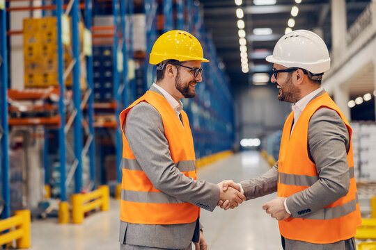 Two businessmen making agreement and shaking hands in warehouse.