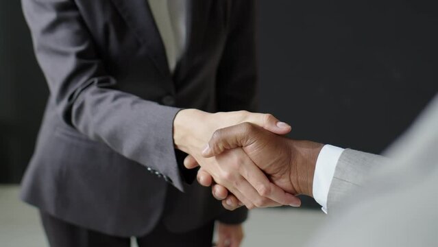 Cropped shot of handshake of diverse businessman and businesswoman cooperating in office