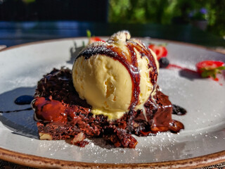 Close-up of a scoop of ice cream on a piece of brownie beautifully served on a dessert plate. Food presentation