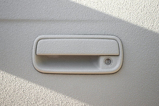 Door handle on a white car door coated with a 2-component heavy-duty protective paint for extreme conditions, raptor paint.