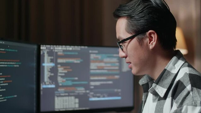 Close Up Of Asian Male Programmer Smiling To Camera While Creating Software Engineer Developing App, Program, Video Game On Desktop Computer At Home. Terminal With Coding Language 
