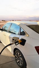 Close up fuel nozzle filled car with fuel, car being filled gasoline at gas station. 