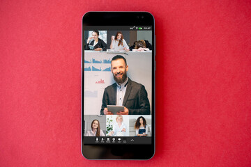 Online presentation. Video chat. Virtual cooperation. Professional business team working on project online on phone screen on red empty space background.