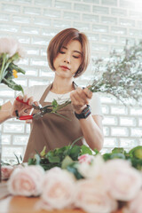 Pretty Asian Korean woman Florist in apron cutting bouquet of flowers in flower shop, Making decorations and arrangements flowers, Small business, Entrepreneur