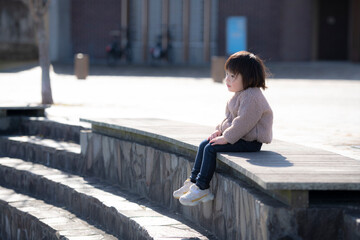 公園のベンチに一人で座っている3歳の女の子
