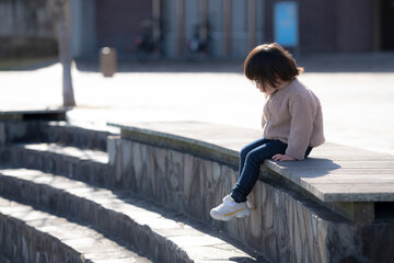 公園のベンチに一人で座っている3歳の女の子