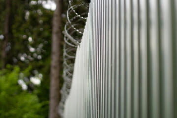 Steel fence with barbed wire. Fence around plant. Private territory. Metal profile. Dangerous wire.