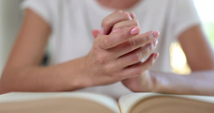 Woman hands in prayer on Bible closeup
