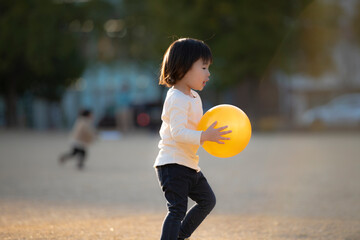 夕方の公園でボール遊びをする女の子