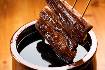 鰻の蒲焼きを秘伝のタレに漬ける
