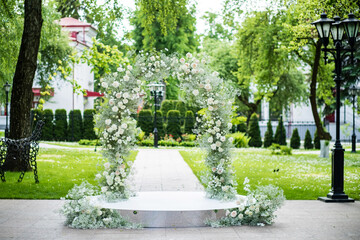 Wedding ceremony in nature with an arch decorated with white flowers