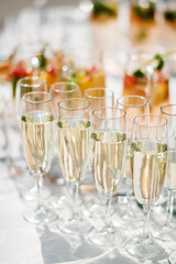 Stylish champagne glasses and food appetizers on table at wedding reception