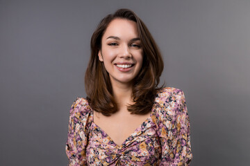 Fototapeta premium Portrait of a young woman on a gray background. Emotional portrait of a model in a stylish shirt