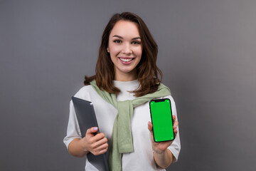 A successful businesswoman with a laptop and a mobile phone on a gray background. Smartphone screen...