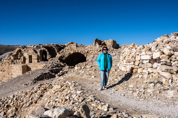 a woman in a blue jacket on the picturesque ancient ruins of a fortress in Jordan