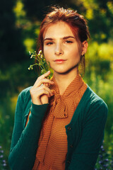 portrait of a beautiful girl with brown hair among the flowers in the field. summer holiday with flowers. countryside