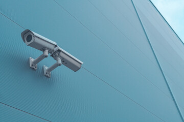 Outdoor surveillance security camera mounted on industrial building wall to monitor the activity...