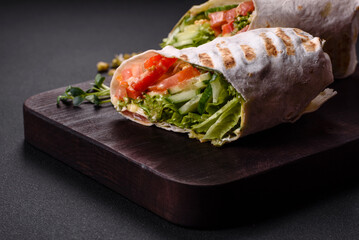 Delicious fresh shawarma with tomatoes, peppers, cucumber on a dark concrete background