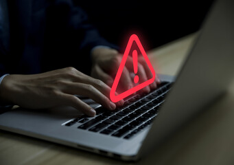 Businessman using laptop showing warning triangle and exclamation sign icon Warning of dangerous...