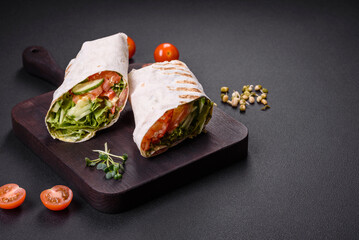 Delicious fresh shawarma with tomatoes, peppers, cucumber on a dark concrete background