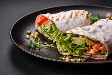 Delicious fresh shawarma with tomatoes, peppers, cucumber on a dark concrete background