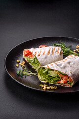 Delicious fresh shawarma with tomatoes, peppers, cucumber on a dark concrete background