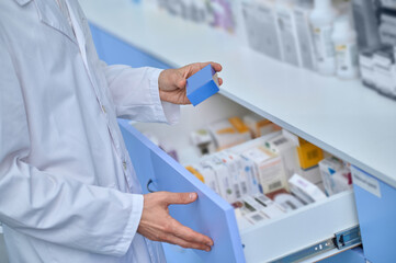Close up picture of pharmacists hand taking a box with medicine