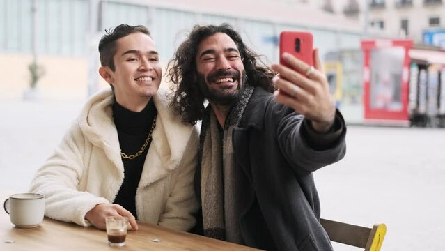Gay couple taking a selfie while grimacing in a cafeteria