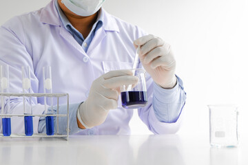 Science innovative Male medical or scientific laboratory researcher performs tests with blue liquid in laboratory. equipment science experiments technology Coronavirus Covid-19 vaccine research