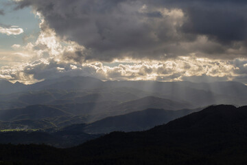 Obraz premium Views of mountains and forests with sunlight shining through the clouds.