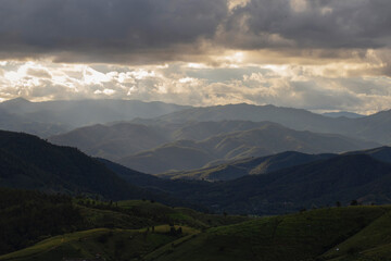 Views of mountains and forests with sunlight shining through the clouds.