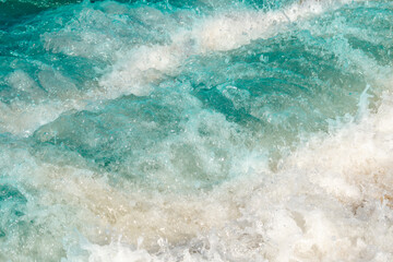 Fototapeta premium Transparent waves run into the sandy beach. Crystal clear water on the beach. Ecologically clean place for a carefree summer holiday.