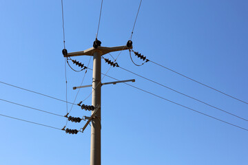 Power line post with electrical wires and capacitors on blue sky background. Electricity...