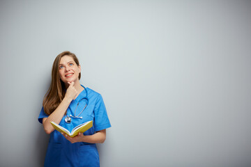 Woman medical student with book touching her chin and looking up.