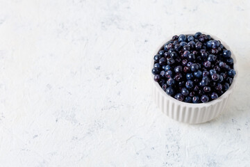Fresh ripe blueberries in white ceramic bowl on table.