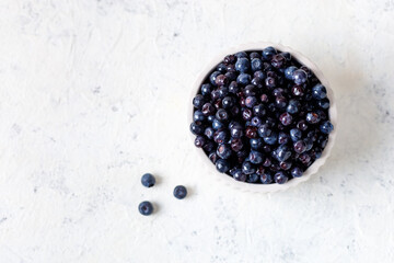 Fresh ripe blueberries in white ceramic bowl on table.