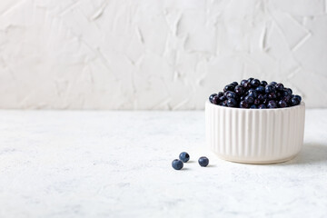 Fototapeta na wymiar Fresh ripe blueberries in white ceramic bowl on table.