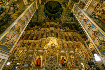 Fototapeta na wymiar Gorgeously decorated altar and frescoes on walls in the interior of Holy Dormition Cathedral in Pechersk Lavra, Kyiv