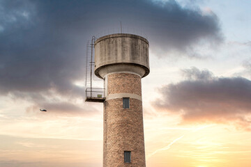 Old-fashioned water tower red brick water tower building blue sky and white clouds sunset sunset