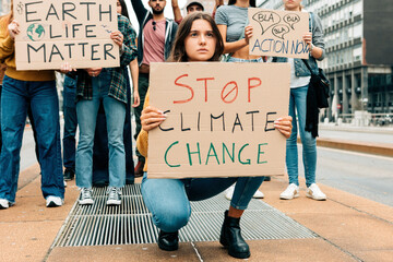 worried young woman holding up a stop climate change placard at a fridays for future street...