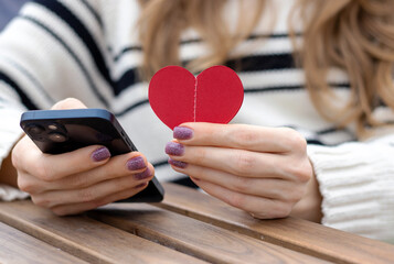 woman sitting in on table with paper hearts garland in one hand using smartphone with another,girl hugging red balloon heart shape.celebrate love valentine day coffee shop inside transparent balloon