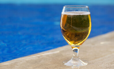 glass with fresh cold beer on pool edge blue color water waves mockup free space for text copy...