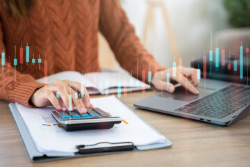 Fototapeta premium Businesswoman working with tablet and using a calculator to calculate the numbers of static in office. Finance accounting concept.