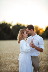 Couple in love and a beautiful wheat field at sunset. Simple light clothing. Summer. Eco.