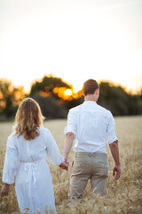 Couple in love and a beautiful wheat field at sunset. Simple light clothing. Summer. Eco.