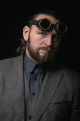 Obraz premium charismatic man in a classic suit and steampunk goggles on a black background stylish Portrait