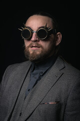 charismatic man in a classic suit and steampunk goggles on a black background stylish Portrait