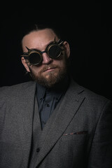 Fototapeta premium charismatic man in a classic suit and steampunk goggles on a black background stylish Portrait