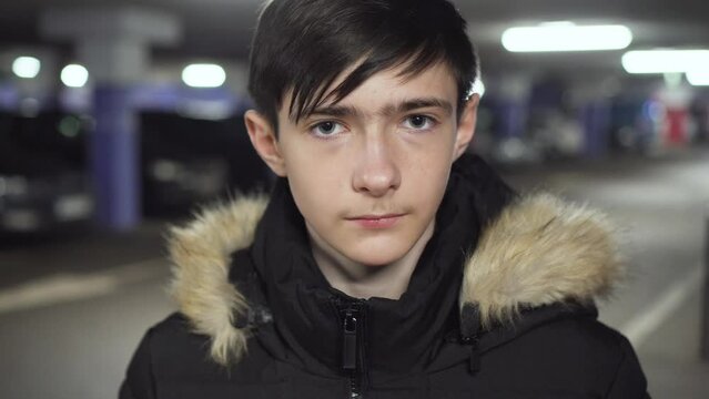 Upset ukrainian refugee boy teen standing in underground parking scared looking at camera during air raid sirens. Concept of peaceful and carefree life without armed conflicts